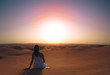 © _KUBE_ - a girl in a dress sits on a hill in the desert and admires the sunset. the view from the back