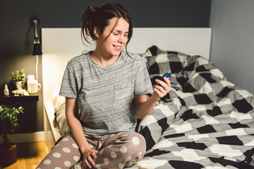 Theme diabetes. young caucasian woman at home in the bedroom on the bed uses the technology of the device for measuring blood glucose, glucometer test strips high sugar level disease