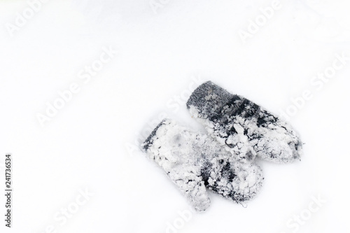 Fotografia A pair of mitten covered with lots of snow lying on a white snow