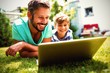 Father and son using laptop in garden