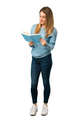 Full body of Blonde woman with blue shirt holding a book and enjoying reading on white background