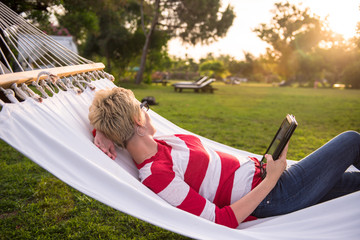 Sticker - woman using a tablet computer while relaxing on hammock