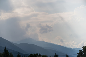 Wall Mural - The sun rays make their way through the stormy sky in the mountain tops