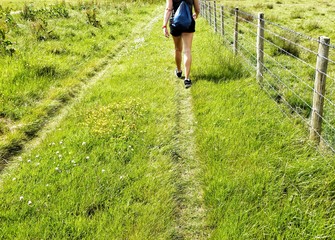 Rear view of a hiker woman walking on the field