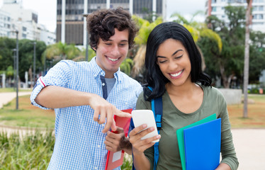 American male student and indian girl looking at mobile phone