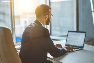 The businessman sitting at the table with a modern laptop