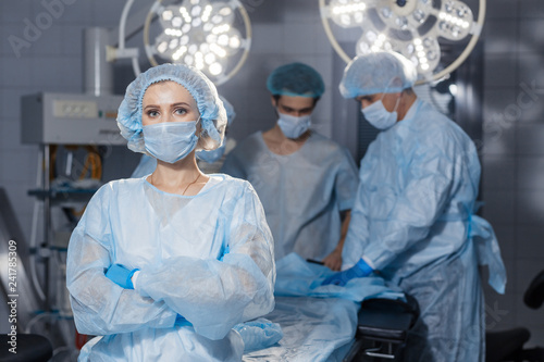 Cuadros en Lienzo Portrait of concentrated female surgeon in surgical uniform and mask at operating room