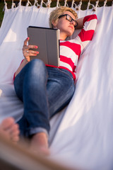 Sticker - woman using a tablet computer while relaxing on hammock