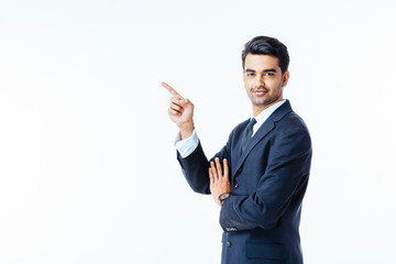 Portrait of a smiling, successful businessman in black suit and tie pointing up isolated on white background
