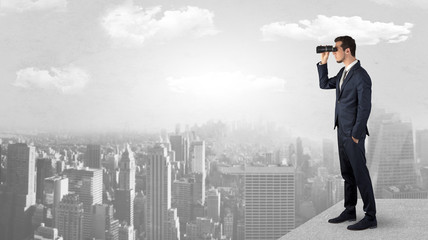 Wall Mural - businessman looking forward to a city with binoculars from skyscraper concept