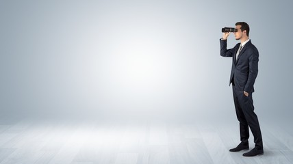 Wall Mural - businessman looking forward with binoculars in an empty space