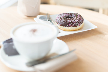 Wall Mural - Chocolate donut with a cup of coffee on table