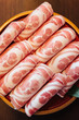 Close up Premium Rare Slices Kurobuta (Black Pig) pork with high-marbled texture on circle wooden plate served for Sukiyaki and Shabu.