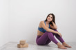© spaskov - Young brunette woman in purple leggings and a sports t-shirt does exercises on the floor. Balances on the blocks and near the wall. White room.