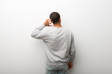 Wall Mural - African american man on white wall background on back position looking back while scratching head