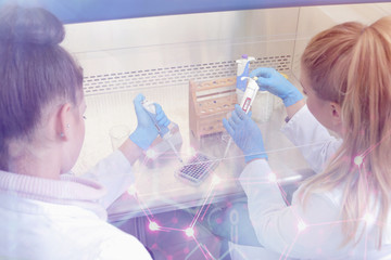 Two young female Laboratory scientists working at lab with test tubes and microscope, test or research in clinical laboratory.Science, chemistry, biology, medicine and people concept.