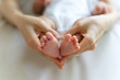© Kawee - Tiny sleeping baby feet in mother hands. Mother hands holding the feet in heart shape. Focus on baby feet. Baby love and care concept.