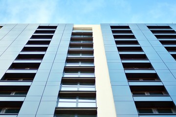 New block of modern apartments with balconies and blue sky in the background