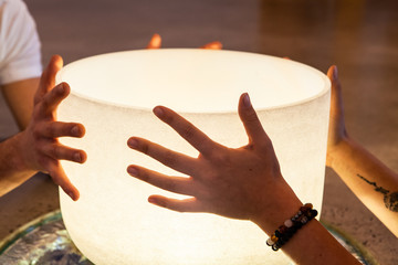 Couple holding a crystal bowl together. Two young hands holding each a side of a crystal ball. The girls wears bracelets. Closeup shot