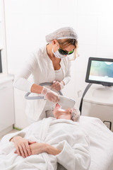 Anti acne phototherapy with professional equipment. Beautiful woman in beauty salon during photo rejuvenation procedure. Laser face skin treatment at cosmetic clinic. Hardware cosmetology