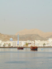 panoramic view on the Muscat corniche with its blue mosque in the back and two traditional dhow boats in the front, Oman, Middle East