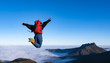© poliki - Cheering happy young woman jumping on mountain peak cliff edge, Aiako Harriak Natural Park, Basque Country