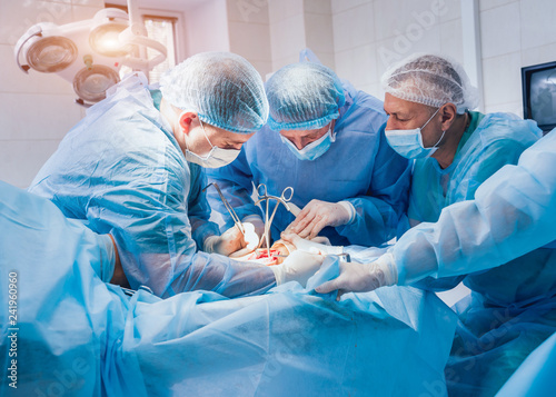 Process of trauma surgery operation. Group of surgeons in operating room with surgery equipment.