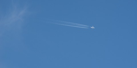 Plane flying on a blue sky, condensation line.