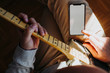 © karrastock - Man teaching himself to play guitar with smartphone