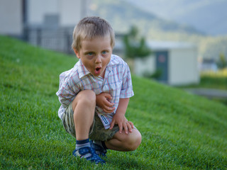 A little boy sitting on a green slope