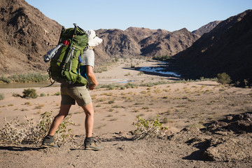 Wall Mural - A lone female hiker with a big backpack hiking in the Namibian desert