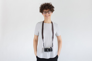 Smiling female photographer with retro film photo camera, standing isolated on gray background