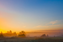 A Large Blue Dawn Sky Over A Field Covered With A Yellow Mist