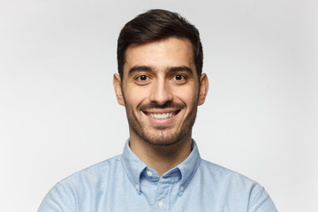Wall Mural - Closeup headshot of businessman standing against gray background, smiling with satisfaction and confidence