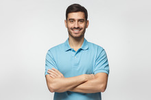 Smiling Handsome Man In Blue Polo Shirt Standing With Crossed Arms Isolated On Gray Background