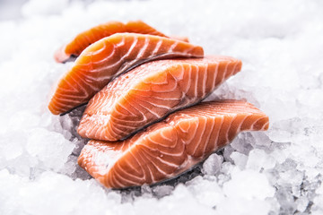 Salmon fillets portioned on ice and empty kitchen board