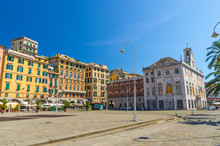 Row Of Colorful Buildings And Palazzo San Giorgio Palace On Piazza Caricamento Square Near Harbor In Historical Centre Of Old European City Genoa Genova With Blue Sky Background, Liguria, Italy