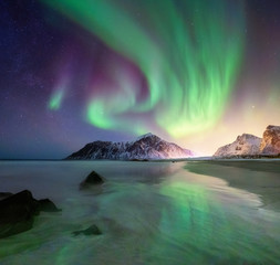 aurora borealis on the lofoten islands, norway. green northern lights above mountains and beach. nig