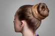 Profile side view closeup portrait of woman with creative elegant brown collected hairstyle, bun hair. indoor studio shot, isolated on grey background.
