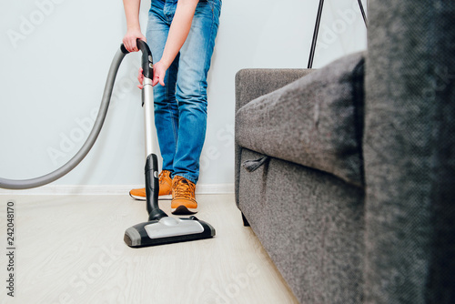 Fotografija The man is vacuuming in the apartment