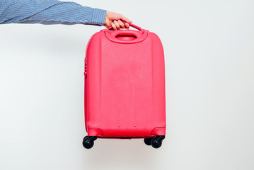 The man is giving by hand A red travel suitcase on wheels, isolated on a white background. Travel concept, packing up before departure. Preparing for travel, going on vacation, break, rest.