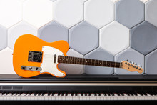 Orange Electric Guitar Laying On Piano