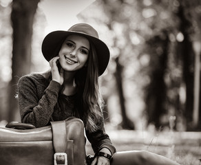 Young redhead woman with suitcase at autumn season park. . Image in black and white color style