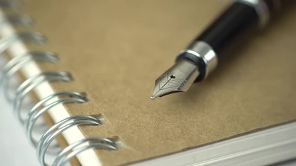 Poster - expensive pen on notebook with a sliding camera move. 4K stock footage.