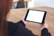 © Farknot Architect - Mockup image of a woman holding and looking at black tablet pc with blank white screen while sitting in office