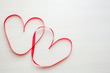 Two red ribbons shaped as heart on wood table