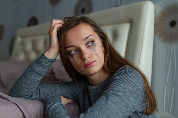Poster - Depressed, sad, lonely woman sitting near the bed and crying because of problems at work and troubles in relationships. Domestic, woman violence. Life problems