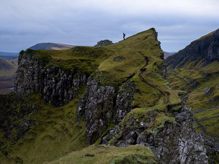 Wall Mural - Single hiker on top of mountain in rugged volcanic landscape around Old Man of Storr, Isle of Skye, Scotland