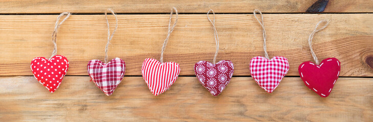 Wall Mural - line of red fabric hearts hanging on old wood background