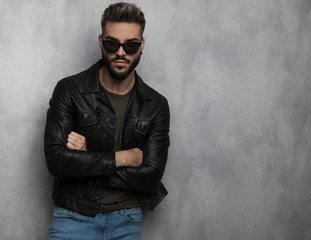 portrait of confident unshaved man wearing leather jacket and sunglasses